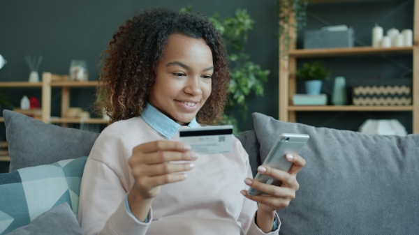 Unsplash – Vitaly Gariev, Young woman holding credit card and smartphone