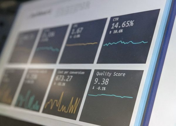 Analyst reviews economic forecasts, probability indicators, and market data on multiple screens.